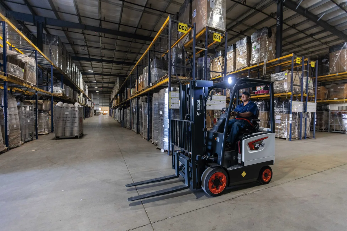 Electric counterbalance forklift working a warehouse aisle