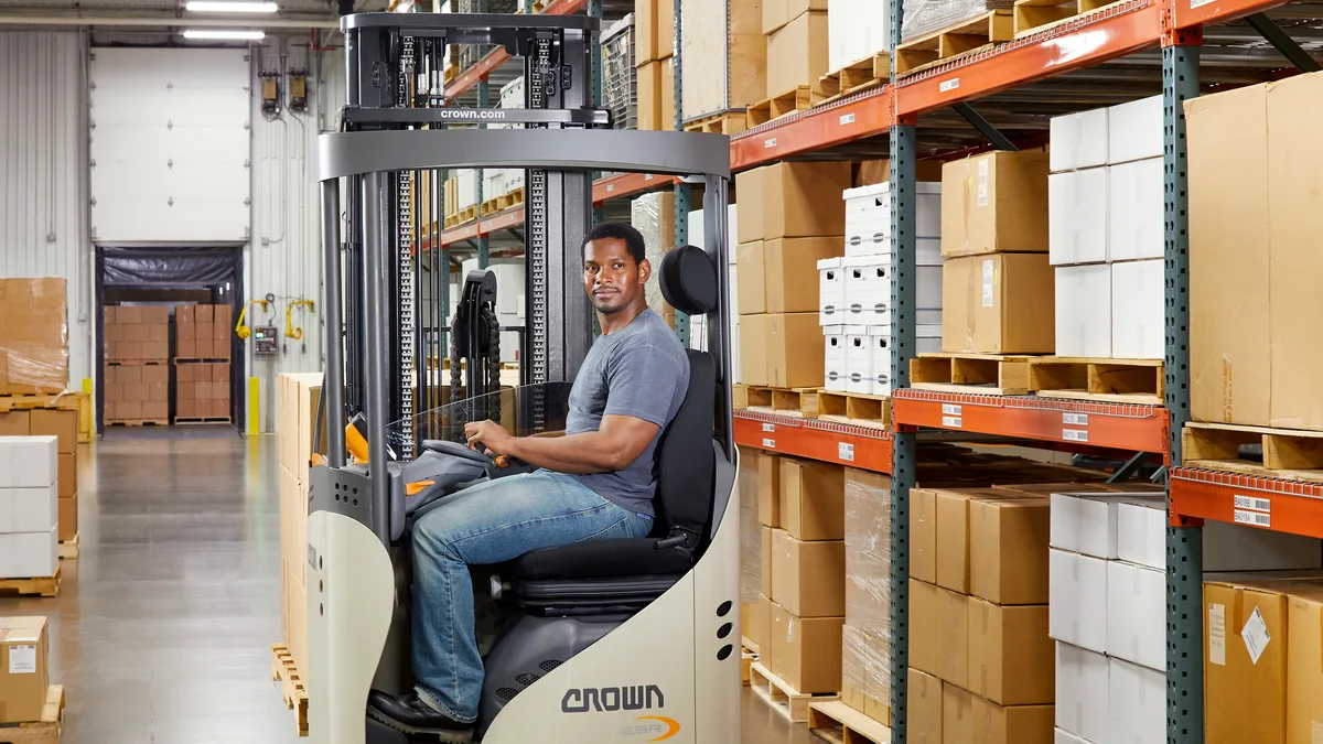 Reach truck working a narrow aisle between loaded racking