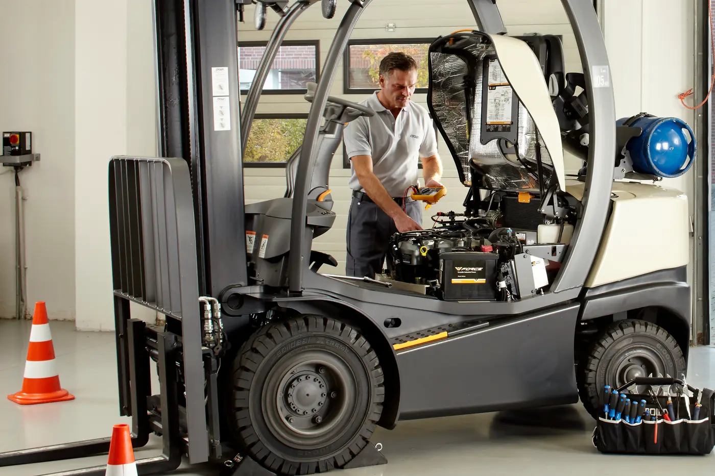 Technician servicing the engine bay of an IC forklift